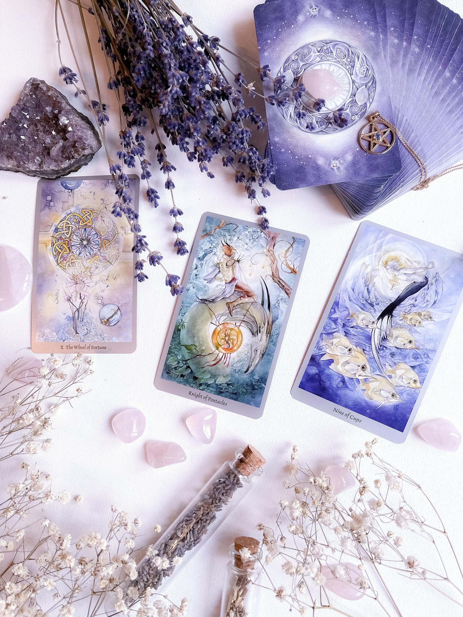 Captivating still life featuring tarot cards, crystals, and dried flowers on a white surface.