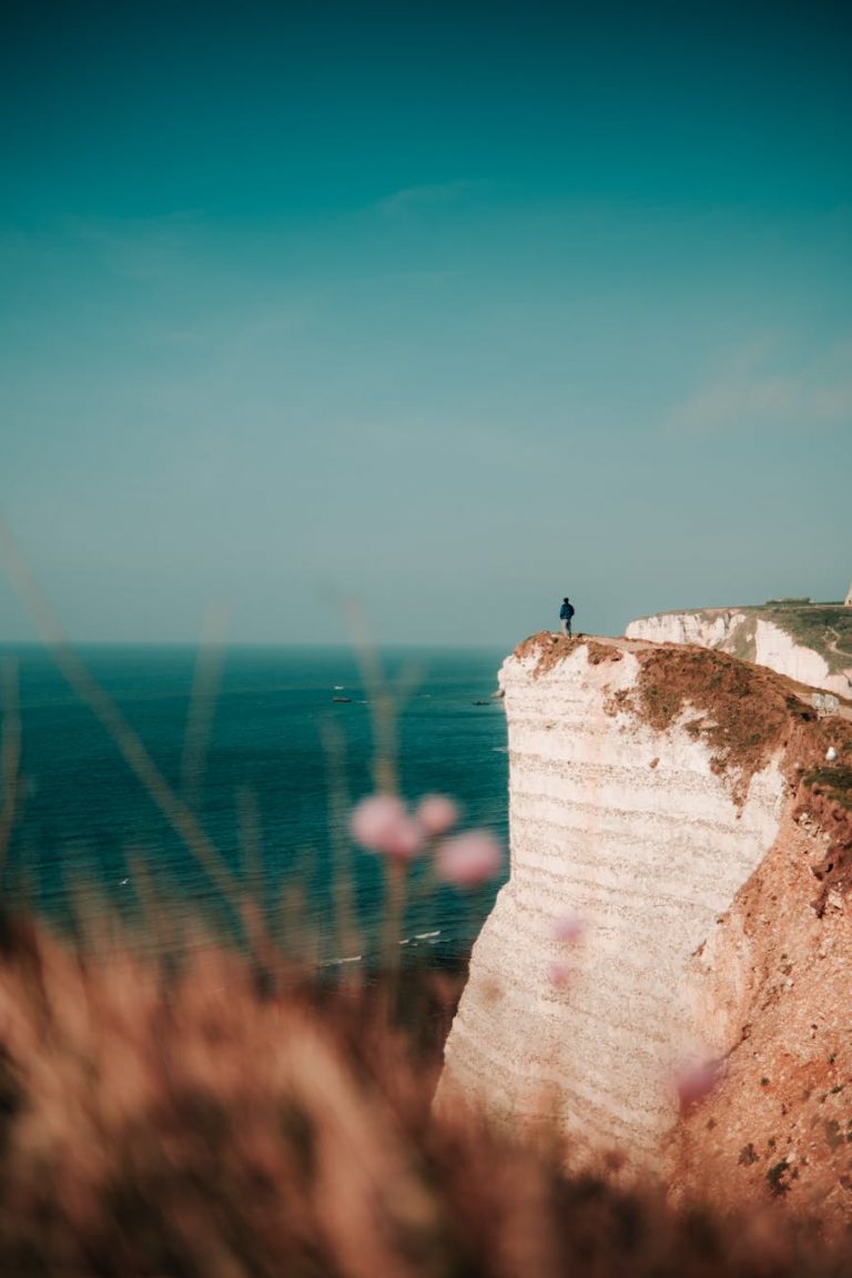 person standing on edge of cliff near sea