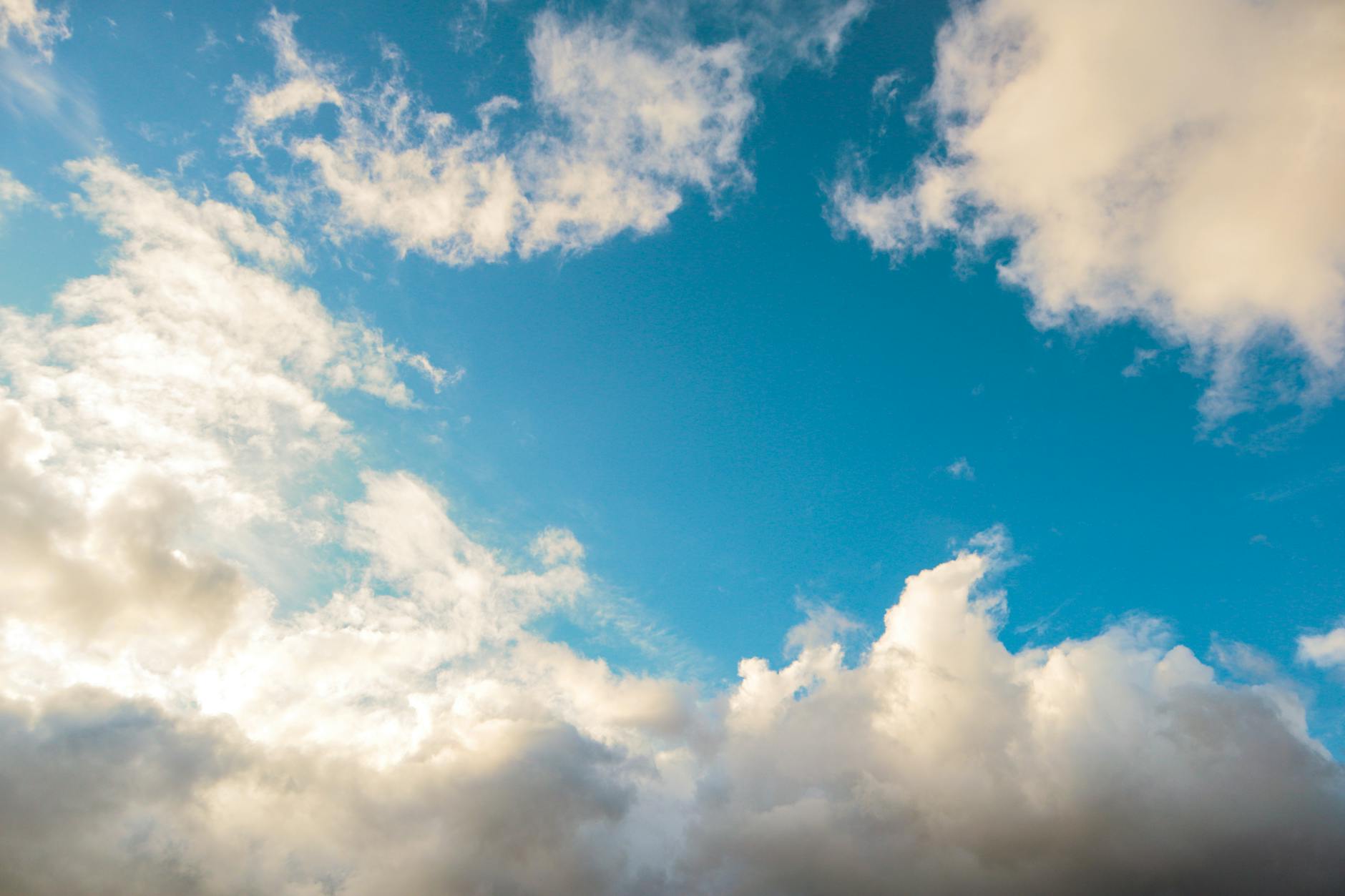 Blue sky with soft white clouds and sunlight.